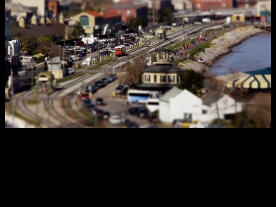 A frame from tilt shift video, showing streetcar along the river