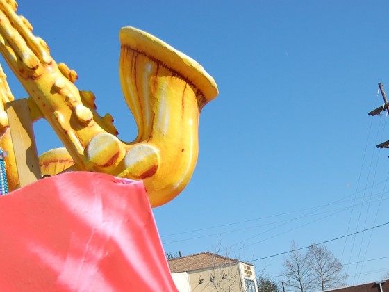 Dad holds up bawling kid to float with saxophone figurehead