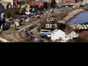 A frame from tilt shift video, showing streetcar along the river