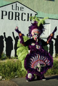 A full dress Mardi Gras Indian stands outside The Porch
