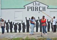 A shot of The Porch's mural shows sillohuettes of children as 3 real life children perform
